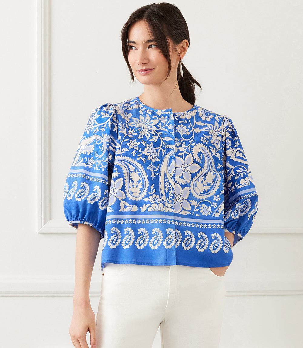 Blue paisley print puff sleeve button-front shirt with pleated back detail worn with white pants