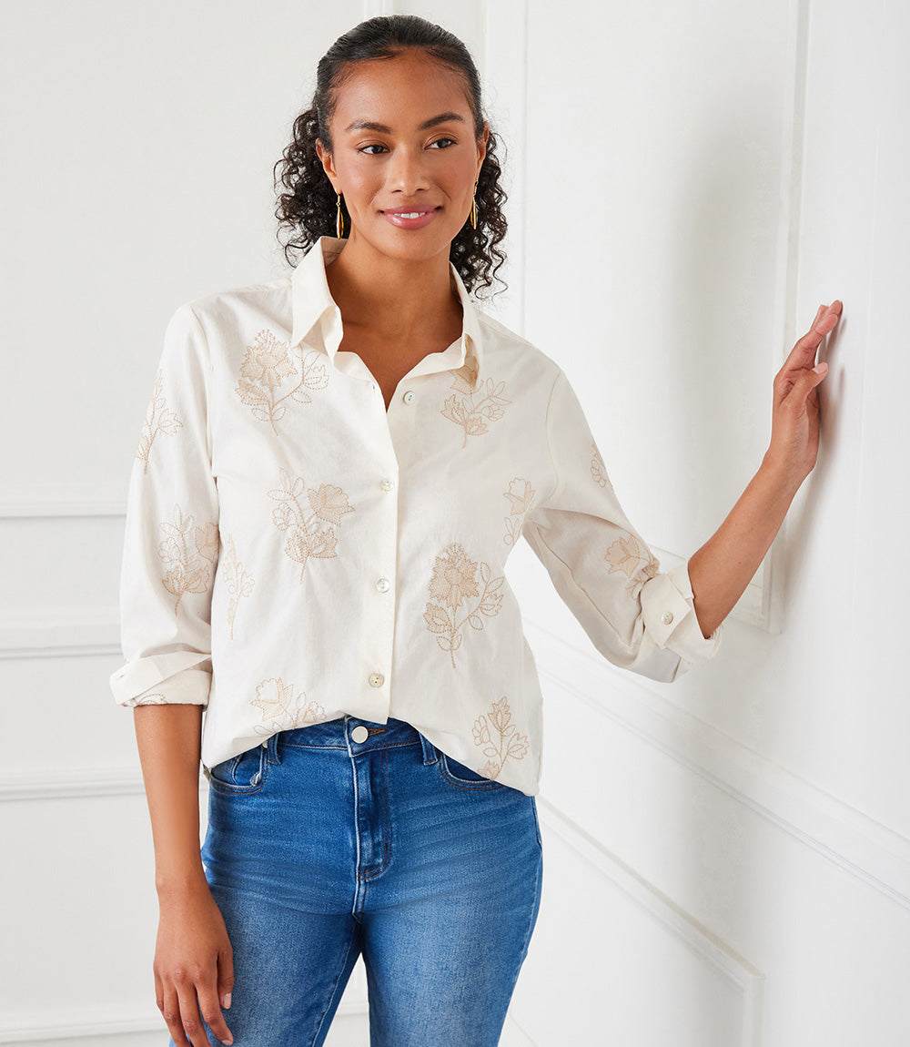 Woman wearing taupe embroidered button-up cotton shirt with long sleeves and collar, styled casually with jeans