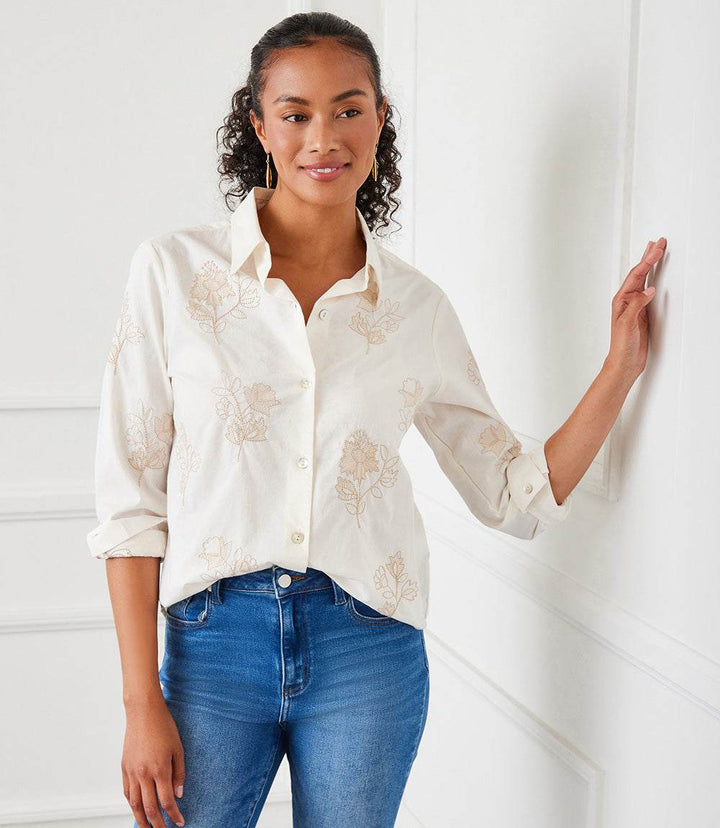 Woman wearing taupe embroidered button-up cotton shirt with long sleeves and collar, styled casually with jeans