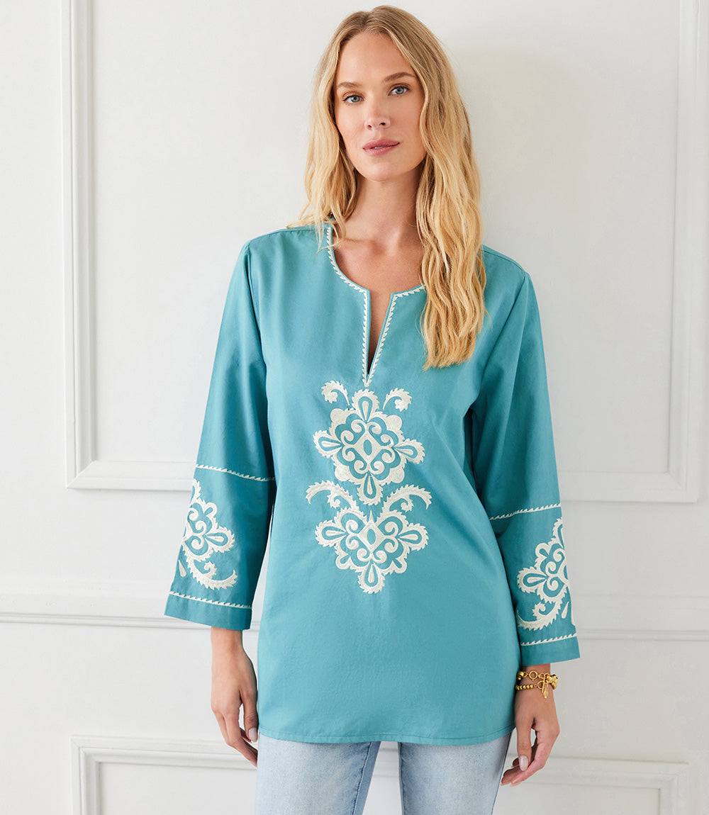 Woman wearing a teal 3/4 sleeve embroidered tunic with cream floral detailing and a split neck, styled for a relaxed casual look.