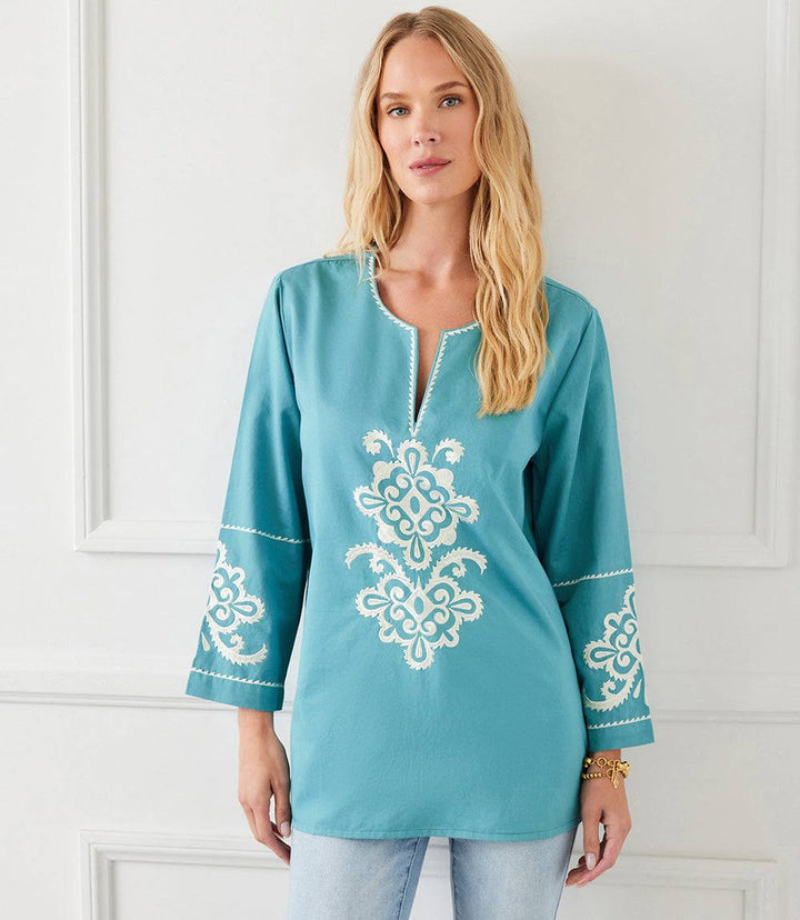 Woman wearing a teal 3/4 sleeve embroidered tunic with cream floral detailing and a split neck, styled for a relaxed casual look.