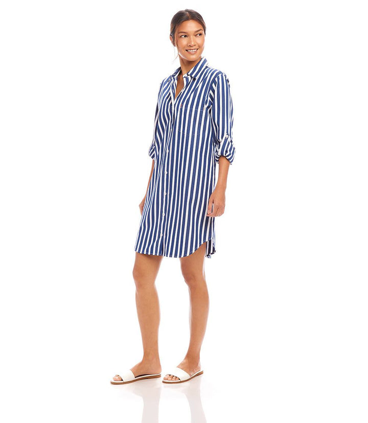 Woman wearing a navy and white vertical striped roll tab sleeve shirtdress with collar and front buttons.