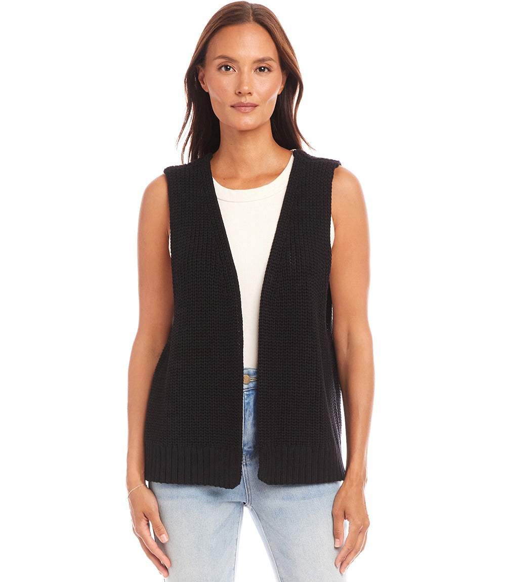 Woman wearing black open sweater vest made of cotton layered over white top with blue jeans