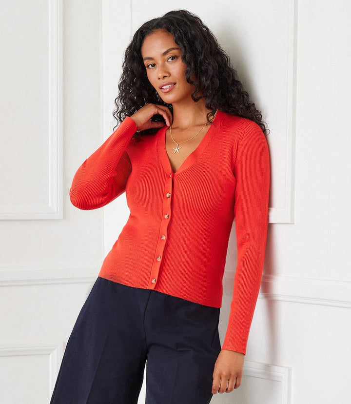 Woman wearing orange ribbed cardigan sweater with button front and V-neck