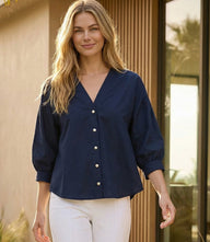 Woman wearing white lantern sleeve pearl button top with V-neck and voluminous sleeves