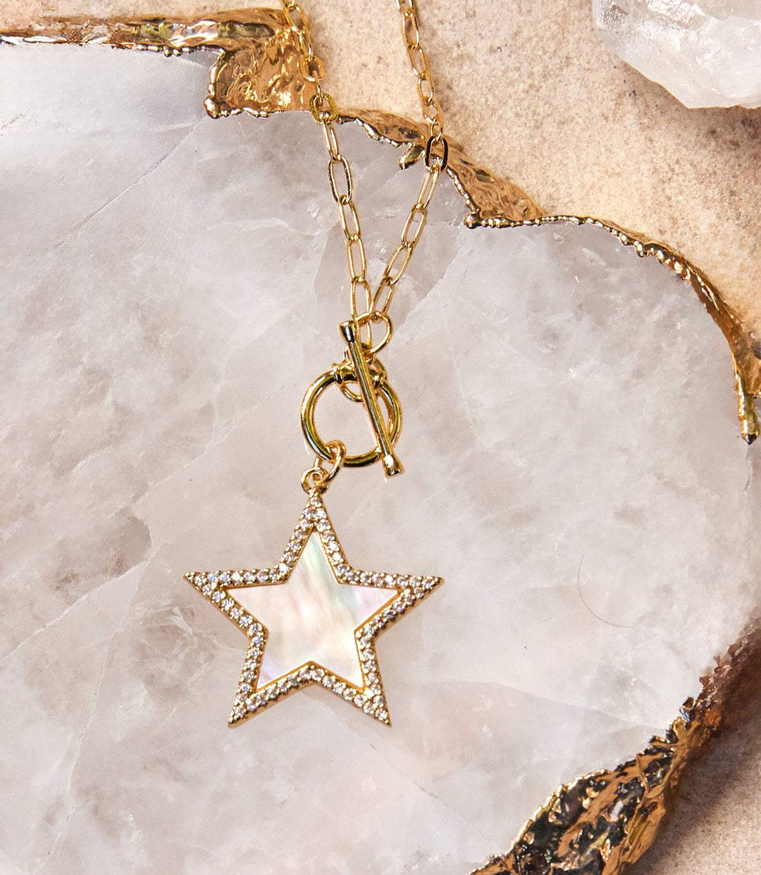 Gold plated Pavé Star Toggle Necklace with mother of pearl star pendant and cubic zirconia crystals on marble background