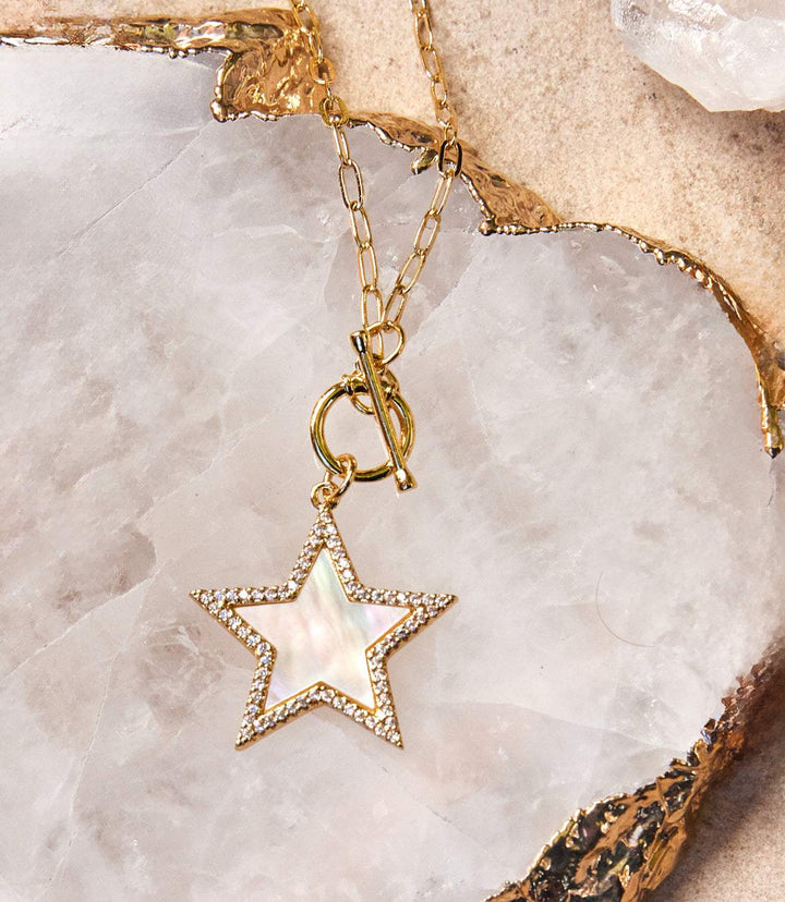 Gold plated Pavé Star Toggle Necklace with mother of pearl star pendant and cubic zirconia crystals on marble background