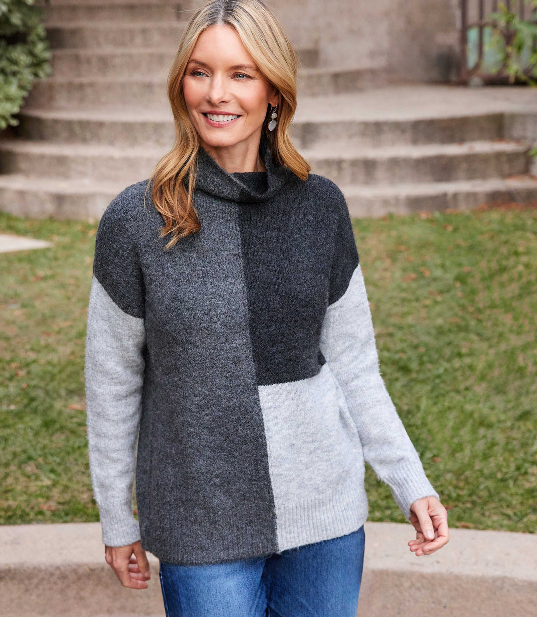 Woman wearing a soft knit colorblock sweater with turtleneck and ribbed cuffs in gray tones