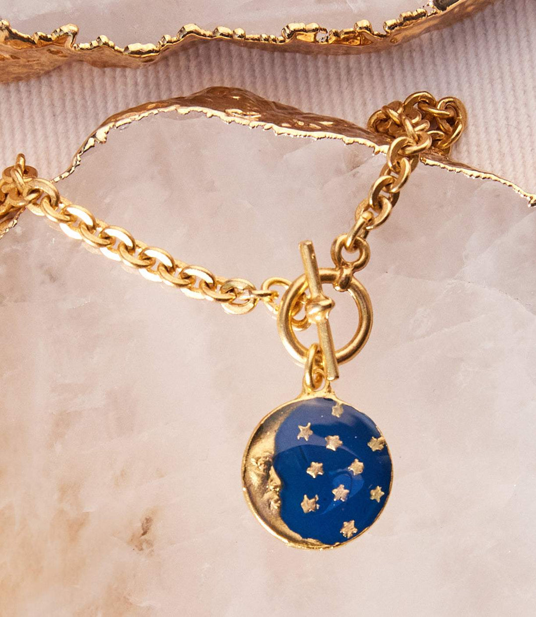 Gold enamel moon and star charm bracelet with navy blue celestial design on brass chain