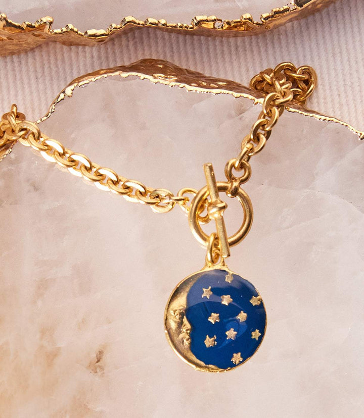 Gold enamel moon and star charm bracelet with navy blue celestial design on brass chain