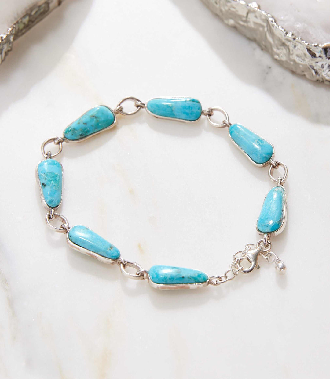 Sterling silver link bracelet with natural blue turquoise stones on marble background