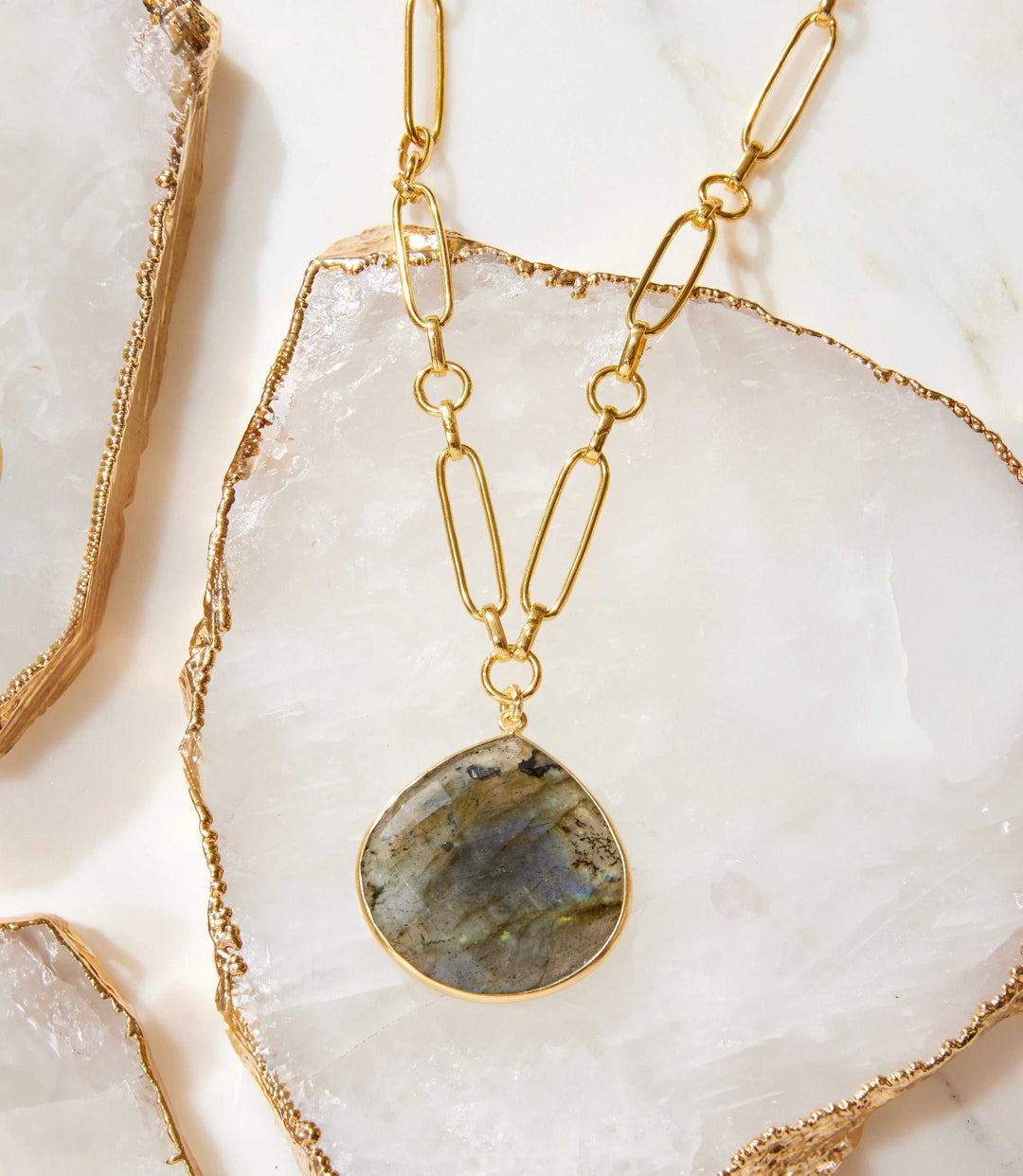 Labradorite pendant necklace with gold plated brass chain on white stone background