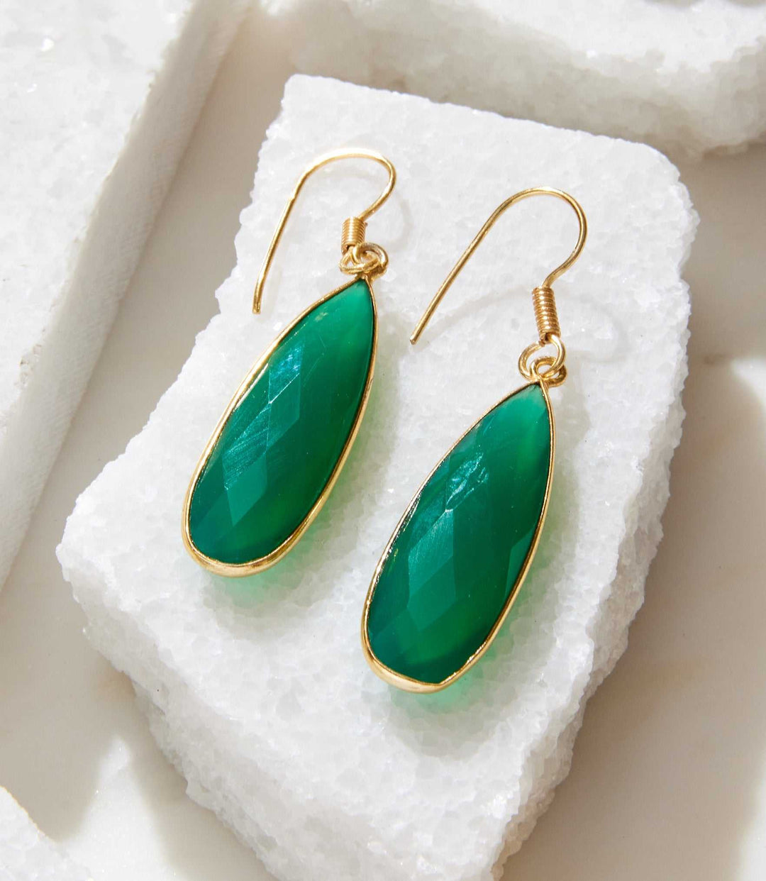 Green Onyx Quartz dangle earrings with gold setting on white stone background
