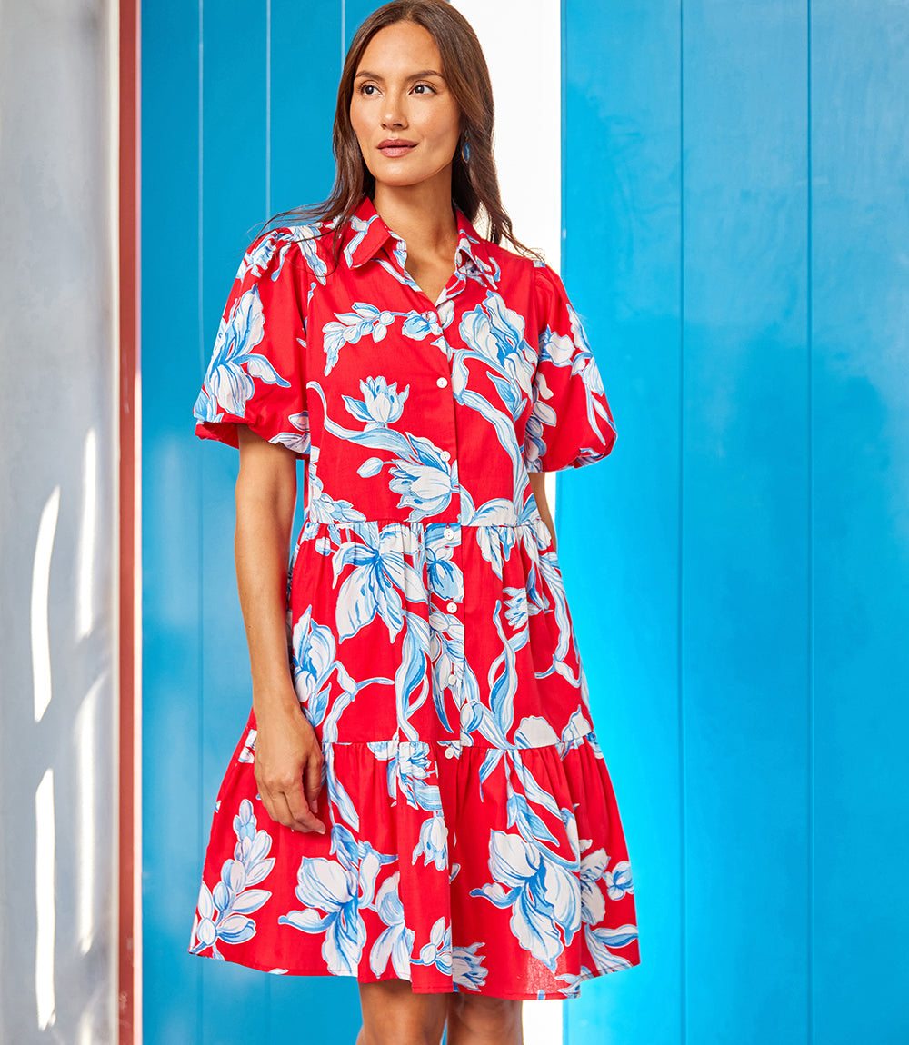 Woman wearing red puff sleeve tiered shirtdress with blue and white floral print and front button closure