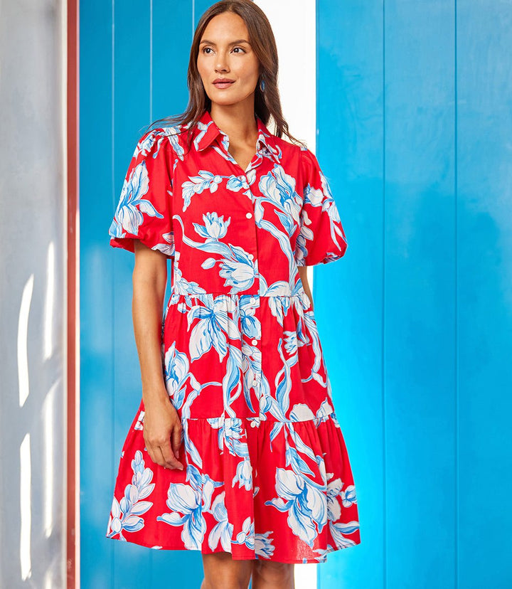 Woman wearing red puff sleeve tiered shirtdress with blue and white floral print and front button closure