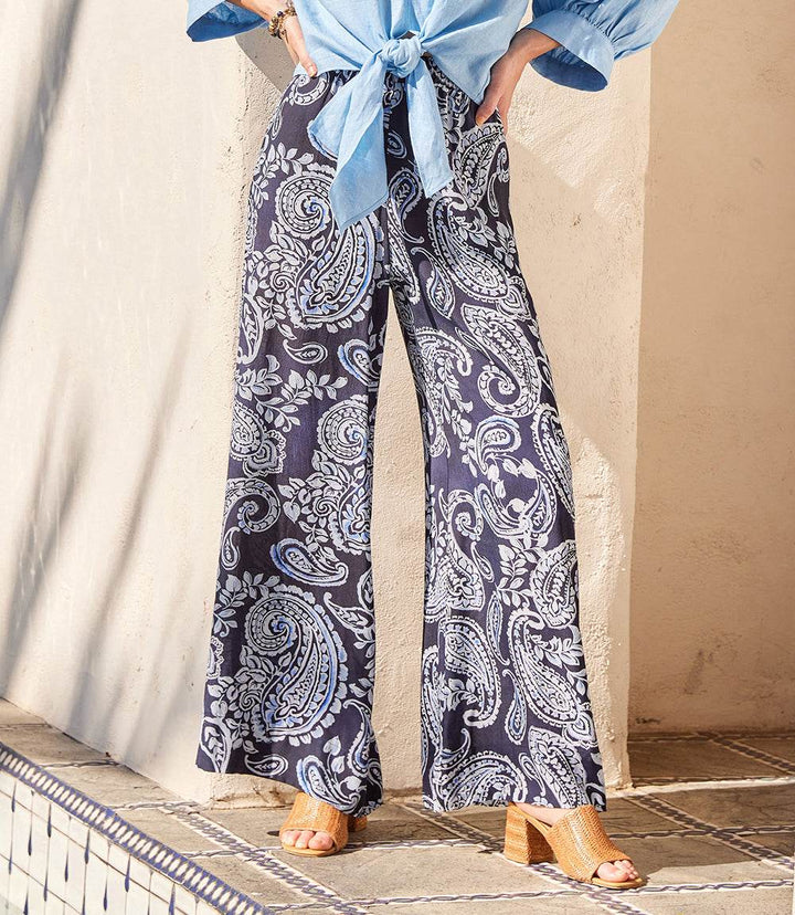 Wide-leg pants with navy and white paisley vine print, elastic waistband, and side pockets on lightweight crepe fabric