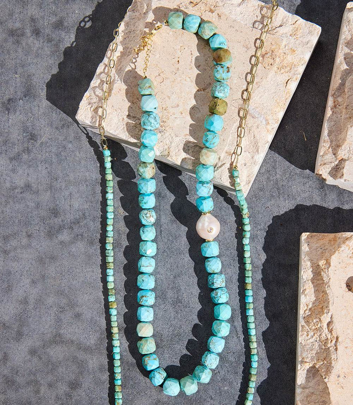 Turquoise and pearl necklace with gold-filled chain on stone background