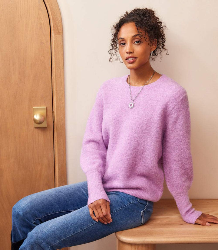 Woman wearing soft lavender boucle blouson sleeve sweater with scoop neck and ribbed cuffs sitting indoors