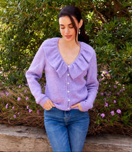Woman wearing lavender ruffle neckline cardigan sweater with front buttons and V-neck outdoors