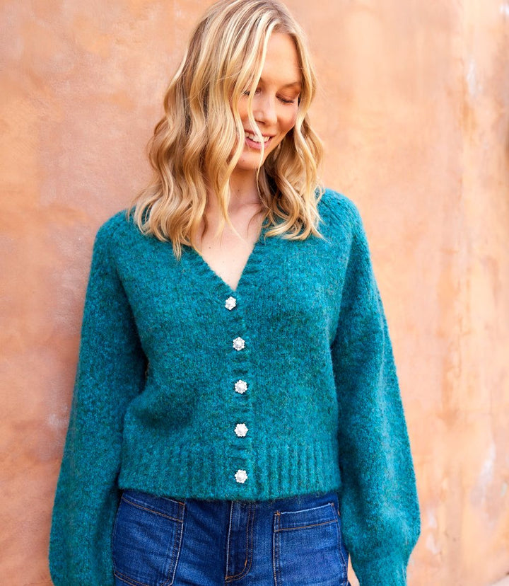 Woman wearing teal Pearl Button Cardigan sweater with ribbed V-neck and pearl-inspired buttons