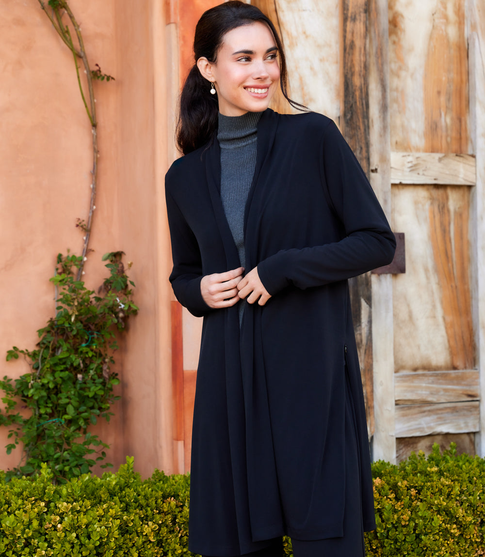 Woman wearing black Travel Jersey adjustable zip jacket with open front and side zipper details outdoors