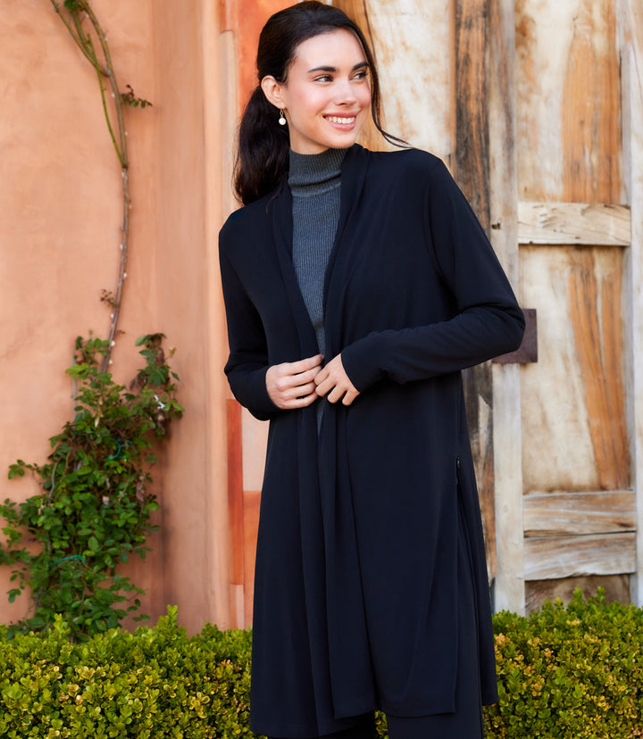 Woman wearing black Travel Jersey adjustable zip jacket with open front and side zipper details outdoors