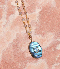 Amazonite amulet necklace with oval pendant, labradorite, aquamarine accents, and gold vermeil chain on textured background