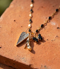 Gold-toned Uptown Girl Charm necklace with pavé heart, high heel, and butterfly charms on black enamel chain