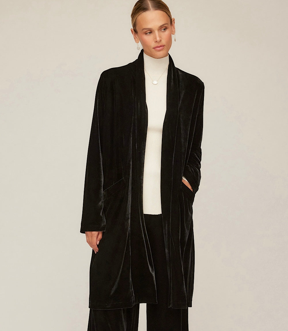 Black velvet duster with open front, long sleeves, side slits, and front pockets worn over white top