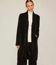 Black velvet duster with open front, long sleeves, side slits, and front pockets worn over white top