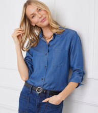 Woman wearing blue ruched 3/4 sleeve button-up shirt with front pocket and tortoiseshell buttons