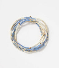 Stack of 7 beaded bracelets with blue, ivory, and gold beads for layered style
