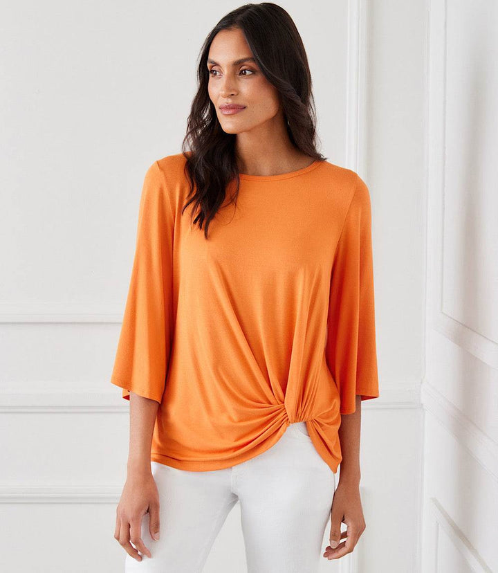 Woman wearing orange flare sleeve pick-up top with twist hem and boat neck