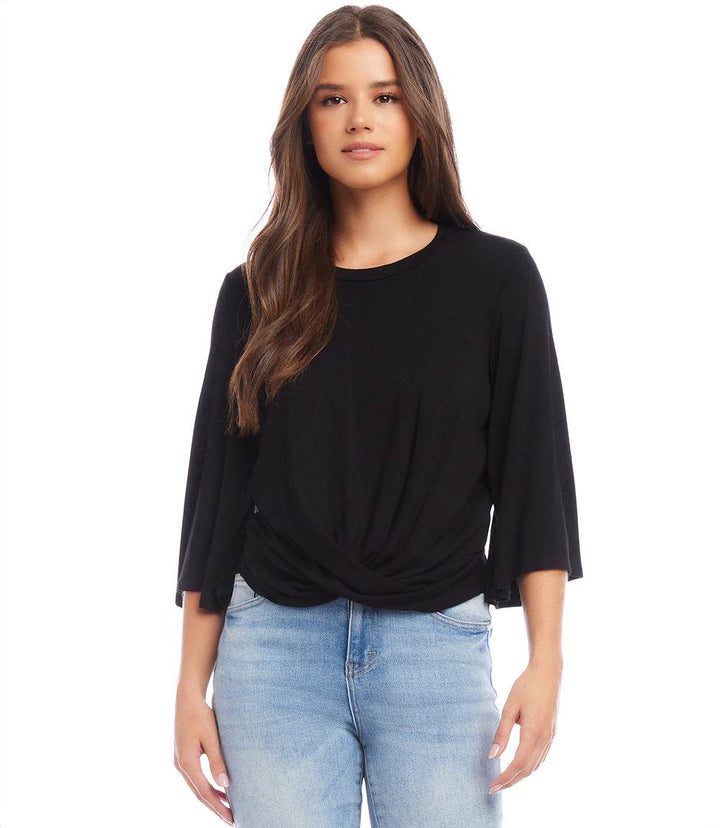 Woman wearing black drape front top with twist seam, bell sleeves, and crew neck paired with light blue jeans