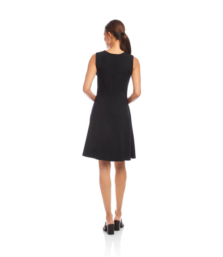 Petite size sleeveless black fit and flare dress with scoop neck and side pockets, modeled from the back.