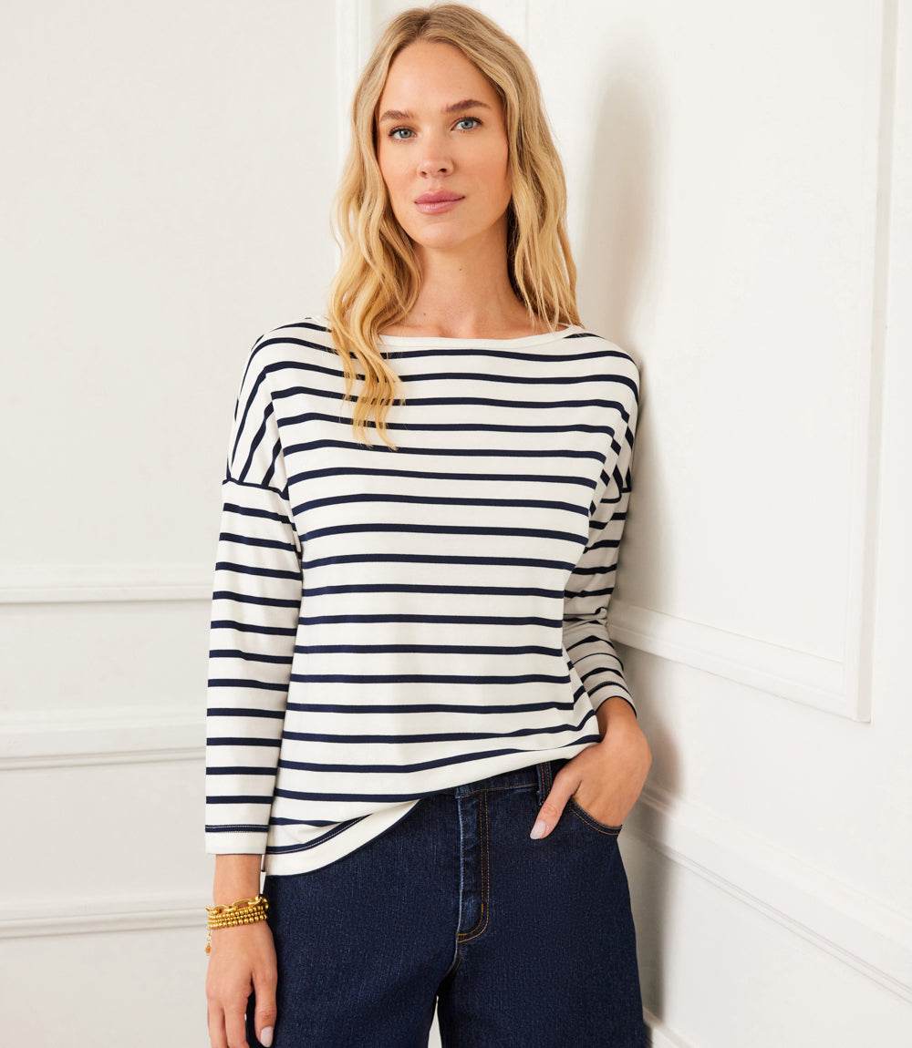Woman wearing navy blue and cream stripe 3/4 sleeve boatneck top with relaxed fit and drop shoulder sleeves.