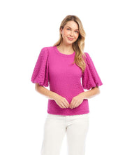 Woman wearing a pink puff sleeve textured top with bubble knit fabric and white pants