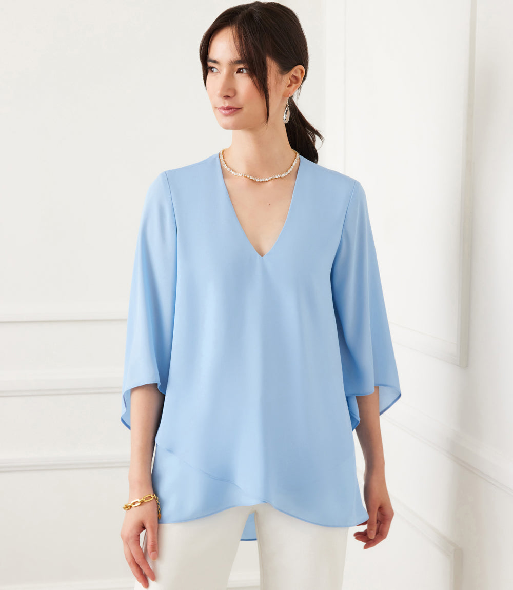 Woman wearing light blue Bracelet Sleeve Asymmetric Top with V-neck and layered hem.