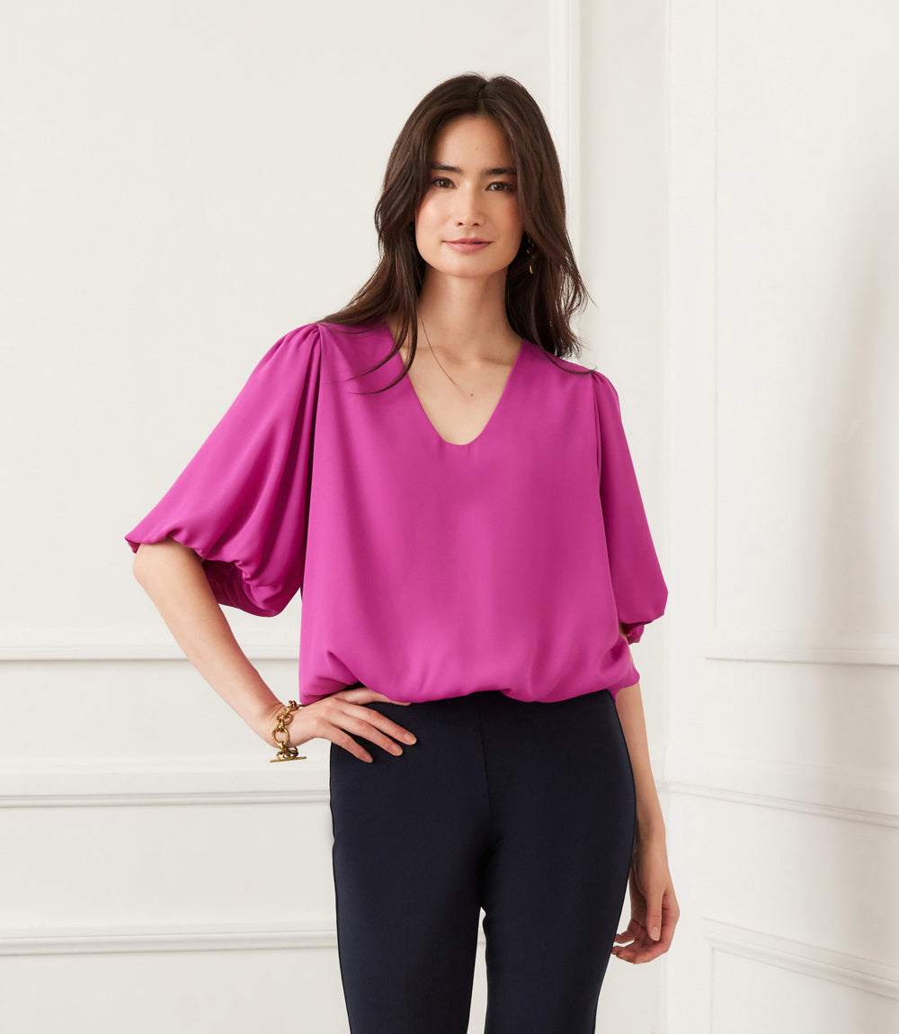 Woman wearing a silky crepe purple puff sleeve top with a V-neck and elasticized hem
