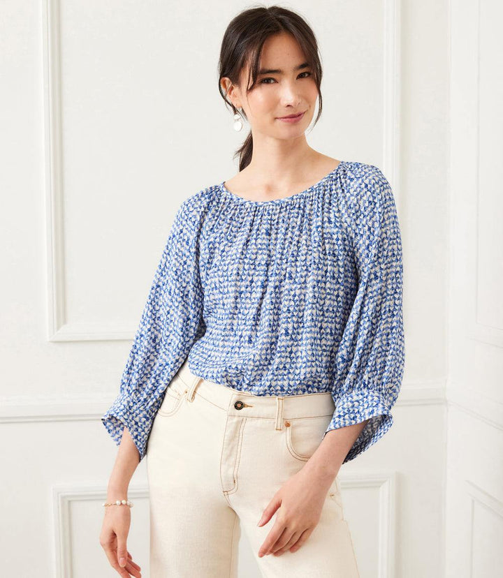 Woman wearing a blue Blouson Sleeve Top with white heart print and boat neck paired with light beige pants