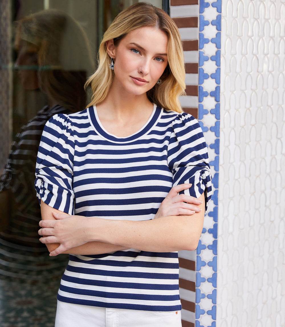 Woman wearing blue and white striped twist-sleeve top with puff sleeves and scoop neck