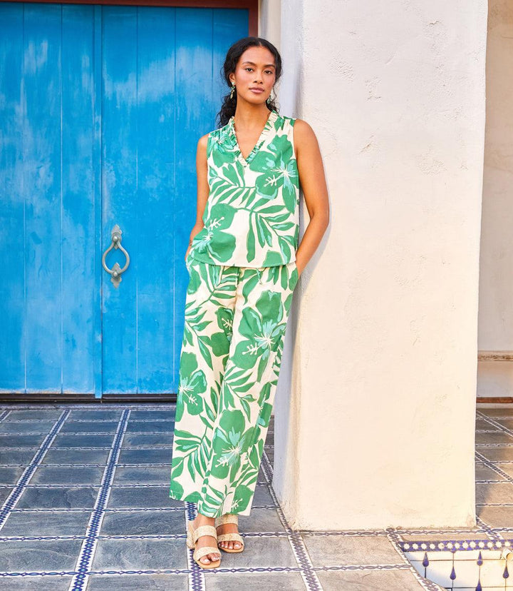 Sleeveless ruffle trim top with green leaf print on beige worn with matching wide-leg pants