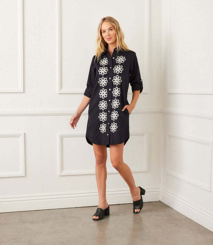 Woman wearing black Roll Tab Embroidered Shirtdress with white floral embroidery, roll-tab sleeves, and side pockets.