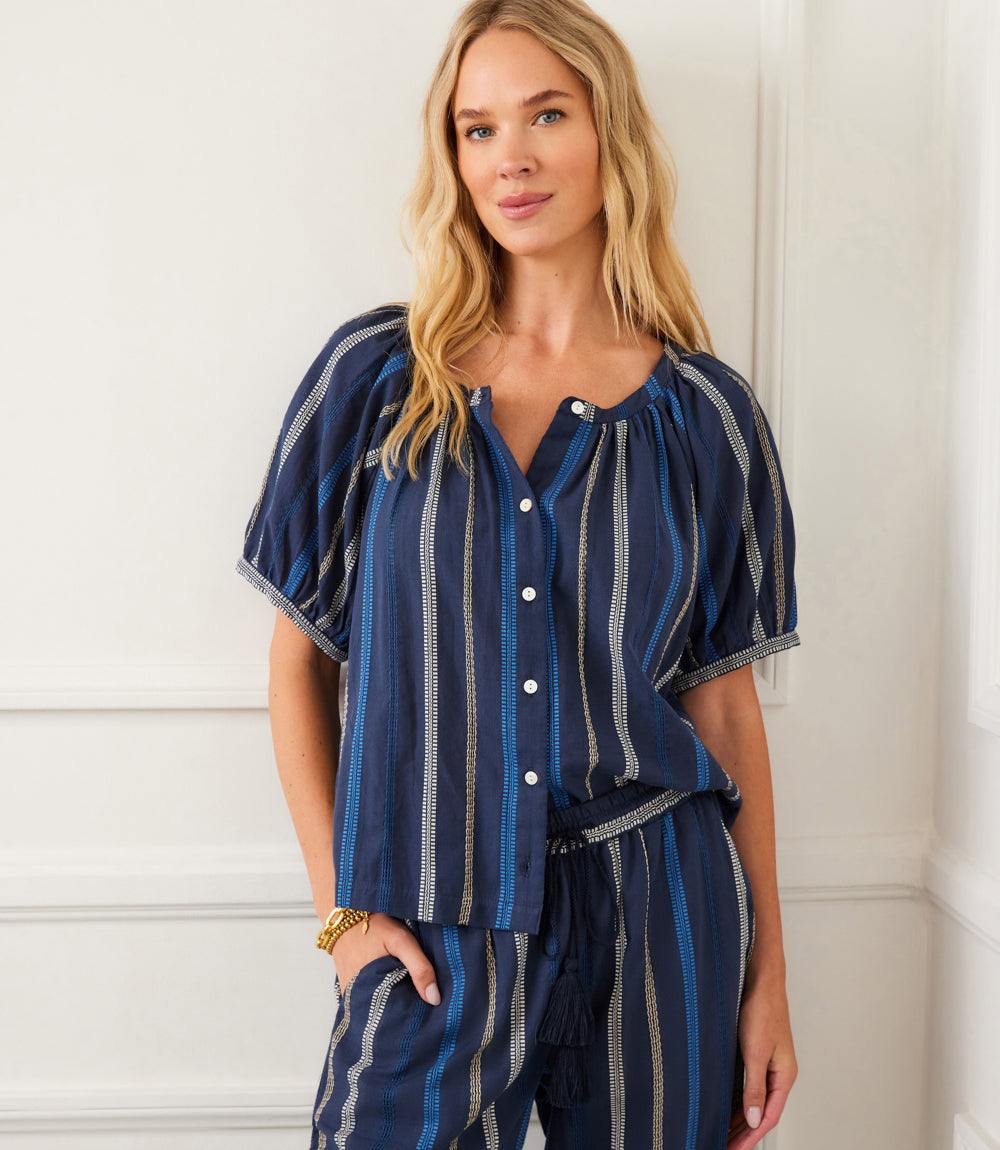 Woman wearing navy embroidered short sleeve top with blue and cream stripes and front buttons closure