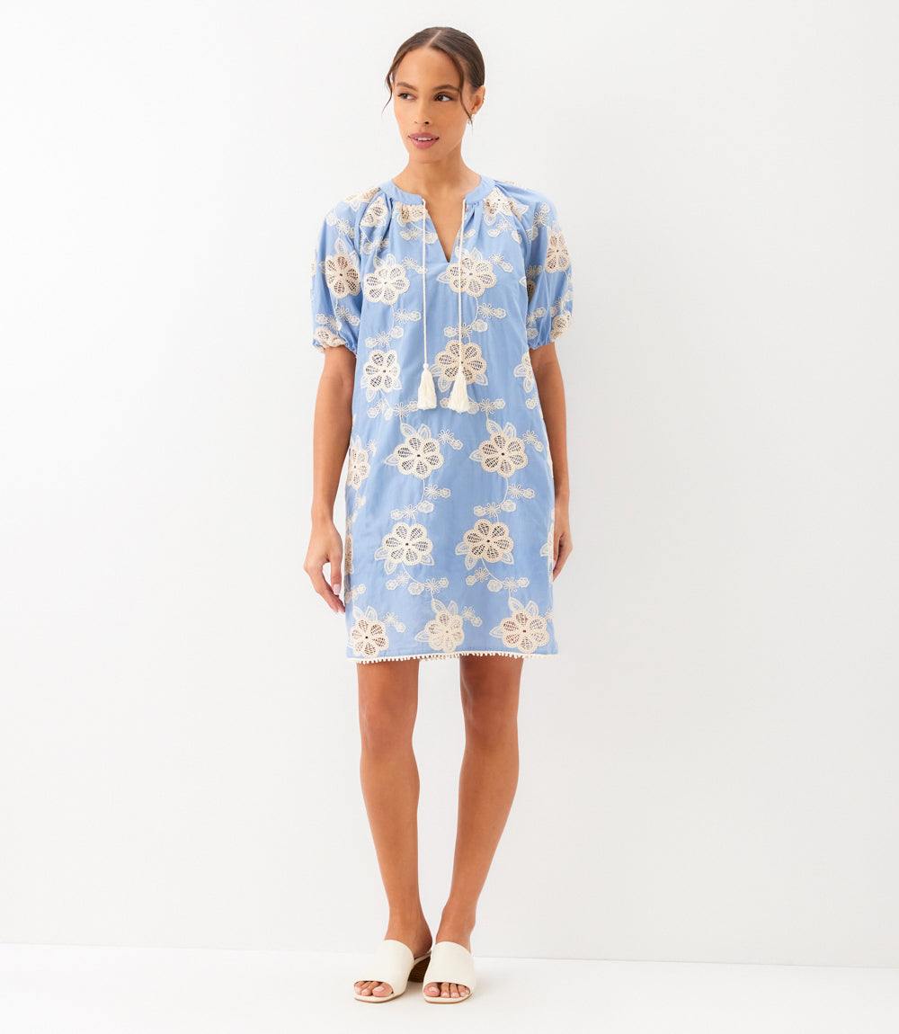 Woman wearing light cotton puff sleeve tassel dress with tie neck and side pockets
