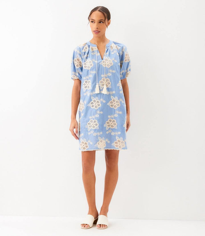 Woman wearing light cotton puff sleeve tassel dress with tie neck and side pockets