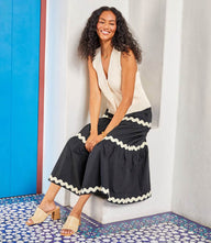 Woman wearing a black Ric-Rac Trim Tiered Midi Skirt with cream trim and a sleeveless cream top sitting on a ledge