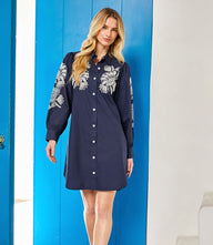 Woman wearing navy embroidered puff sleeve shirtdress with button-down front and floral detailing