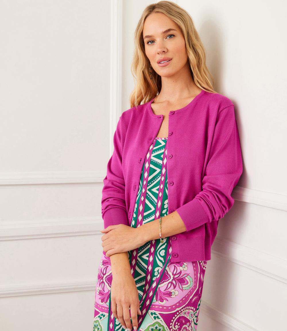 Woman wearing a magenta long sleeve cardigan sweater with button front closure over a patterned dress