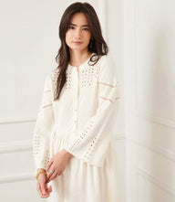 Woman wearing a white flare sleeve embroidered tiered dress with mandarin collar and front buttons